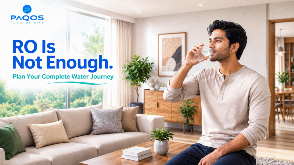 Young Indian man drinking clean water in a modern home, highlighting PAQOS complete water planning beyond an RO purifier.